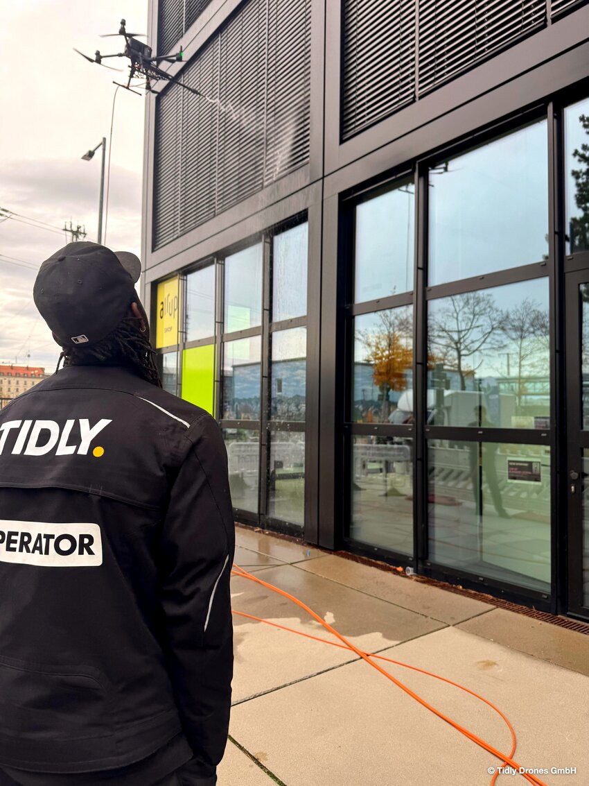 Drohnenpilot steuert Drohne beim Reinigen der Fenster einer Schule | © Tidly Drones