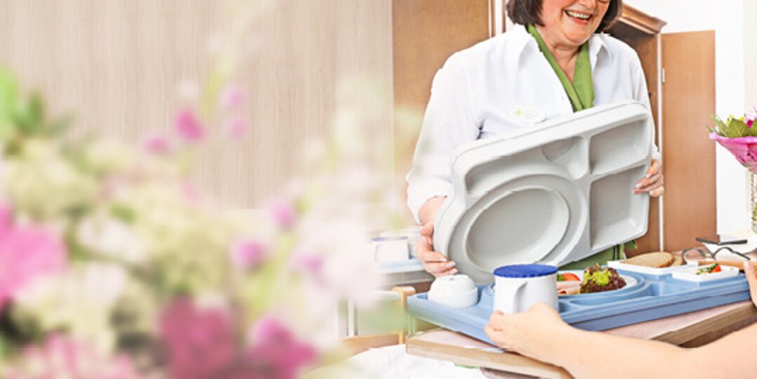 Pflegekraft serviert Patient im Bett Essen