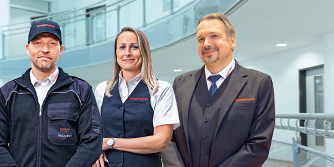 Gruppenbild von drei lächelnden Dussmann-Mitarbeitenden aus dem Arbeitsbereich Sicherheitsdienst.